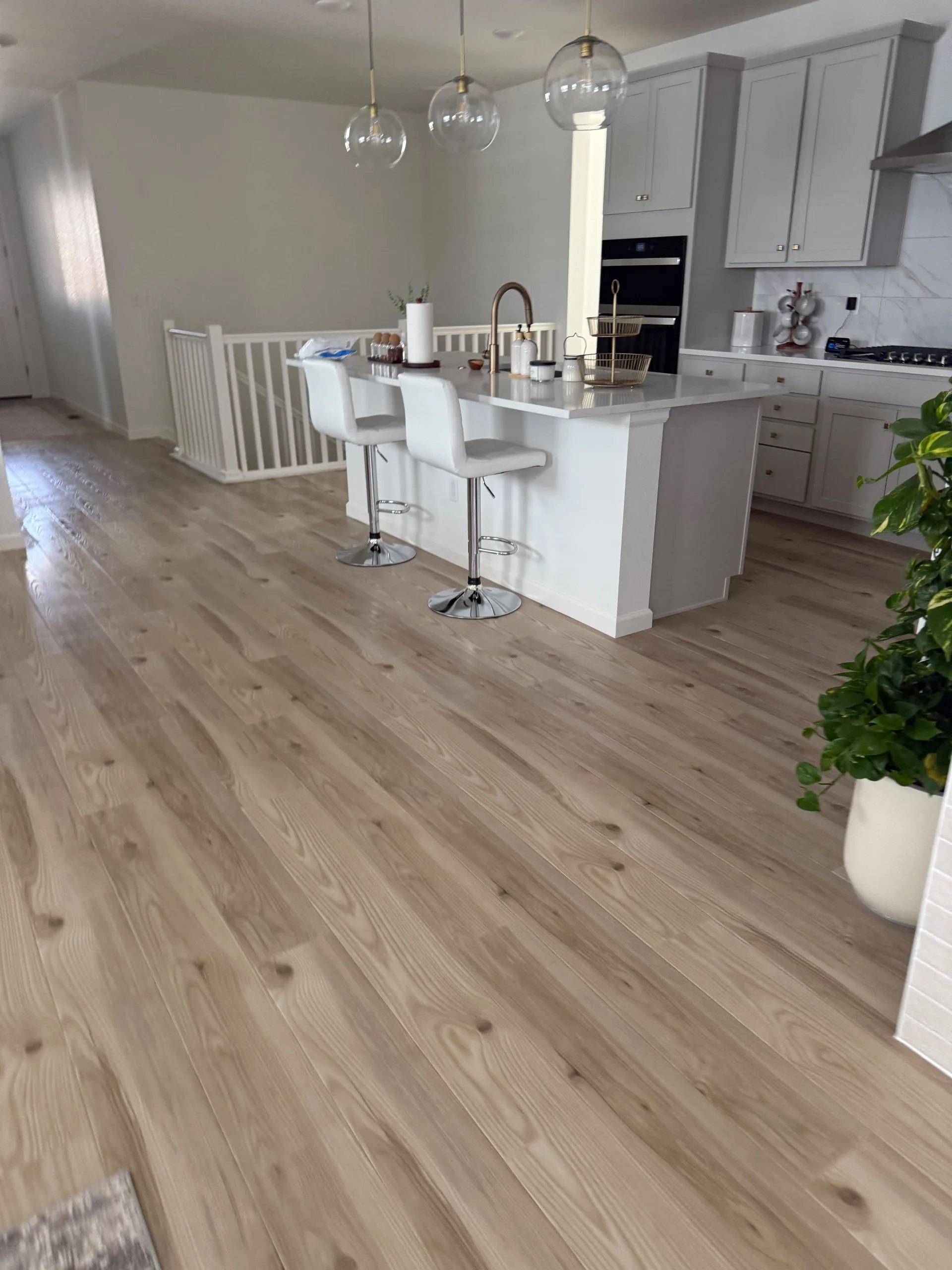 Bright open-concept kitchen with island, bar stools, and gleaming hardwood floors after a Romero Cleaning residential service