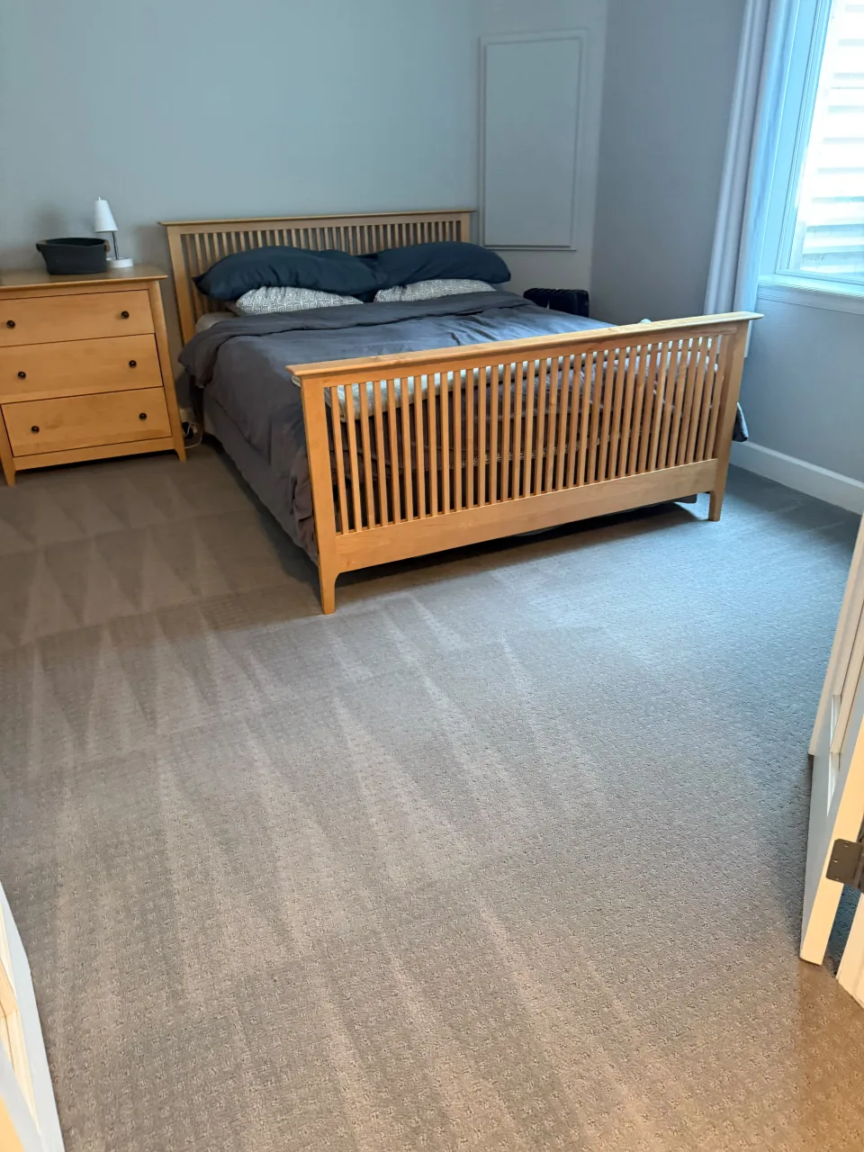 Empty room with a wooden bed and dresser, spotless carpet, ready for move-out