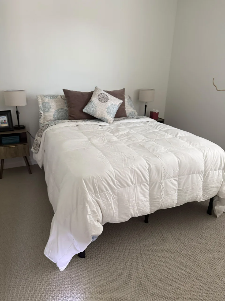 Clean bedroom with a neatly made white bed, nightstands and lamps, tidy space after residential cleaning