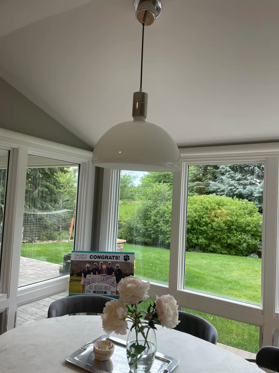 Bright dining room next to large windows with a garden view, table set with flowers, perfect for Airbnb presentation