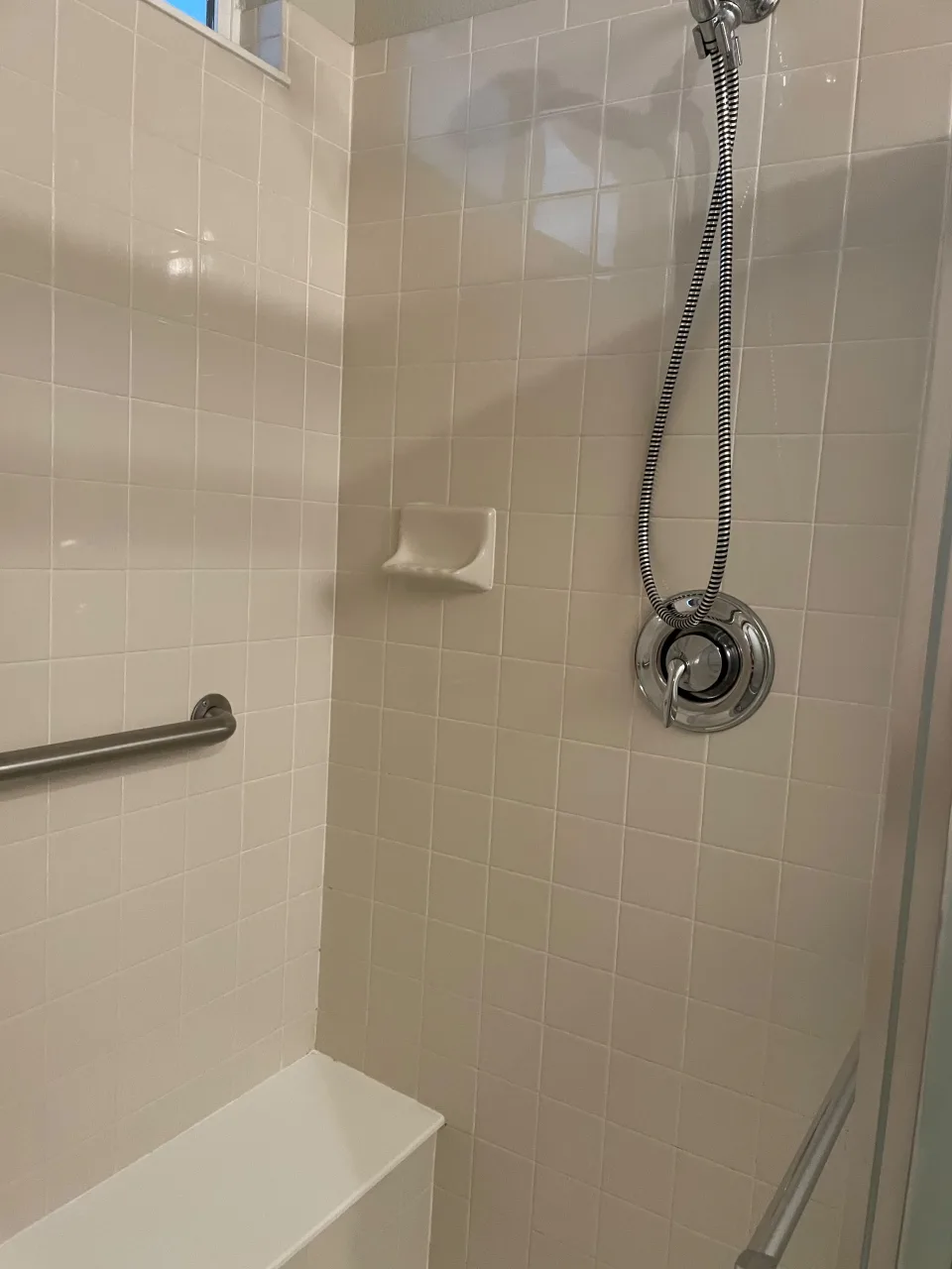 White tiled shower with sparkling chrome fixtures after a deep cleaning